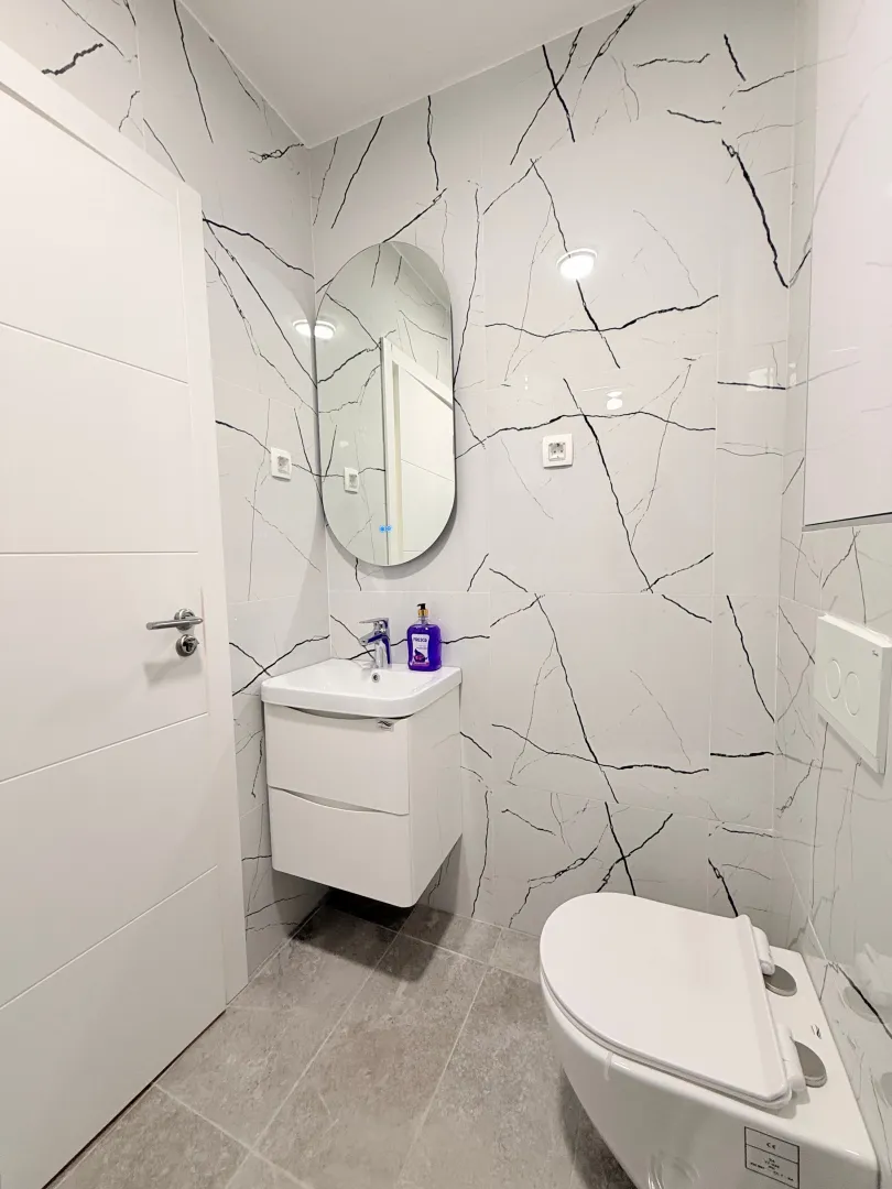 Moderne opremljeno kupatilo sa bijelim pločicama i sanitarijama.