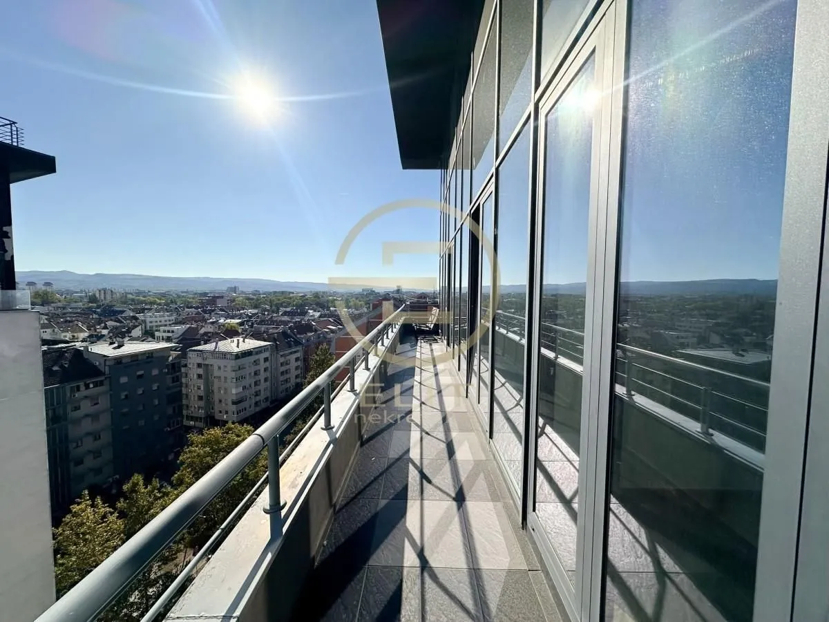 Long tiled balcony with a glass facade and a city view.