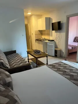 Living room with a sofa, kitchen, and a view of the bedroom. - image 2