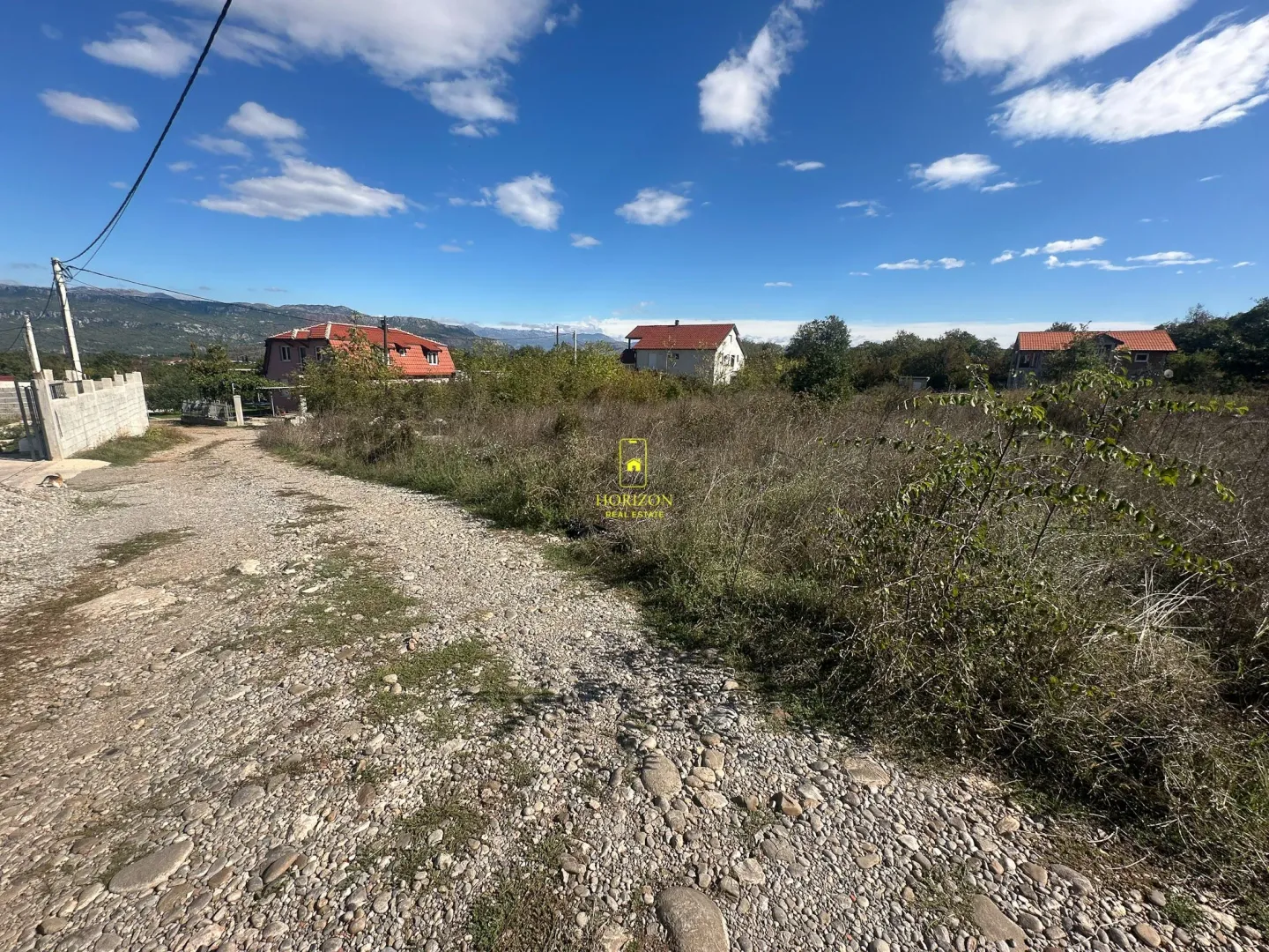 Zemljište sa pristupnim putem i pogledom na okolne kuće i planine.