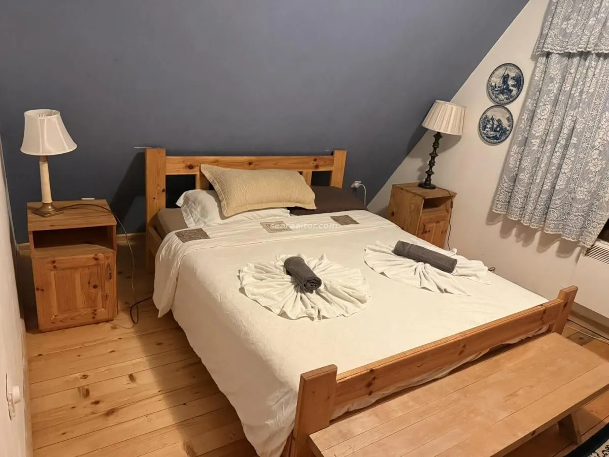 Namještena spavaća soba sa drvenim krevetom i noćnim stočićima.