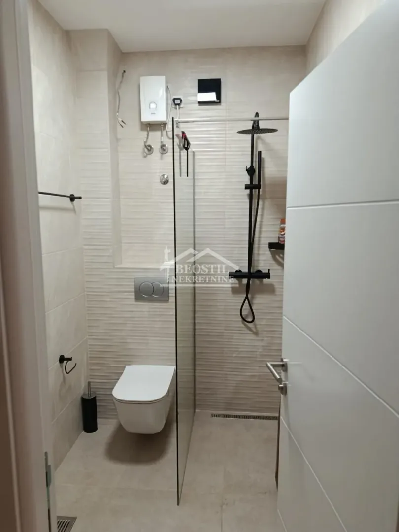 Moderno opremljeno kupatilo sa tuš kabinom i ugradnom šoljom.