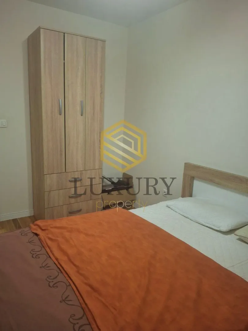 Furnished bedroom with a bed and a wooden wardrobe.