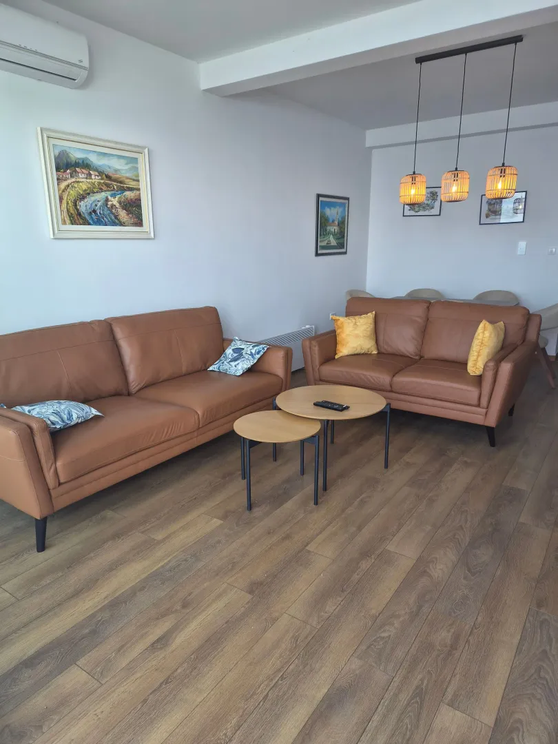 Living room with leather sofas, wooden coffee table, and dining area in the background.