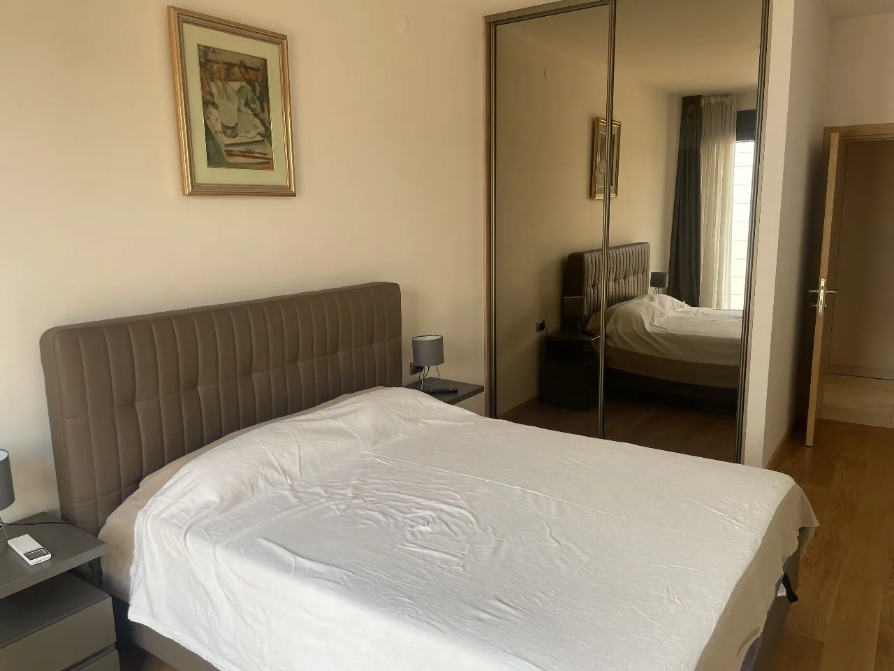 Furnished bedroom with a double bed and a mirrored built-in wardrobe.