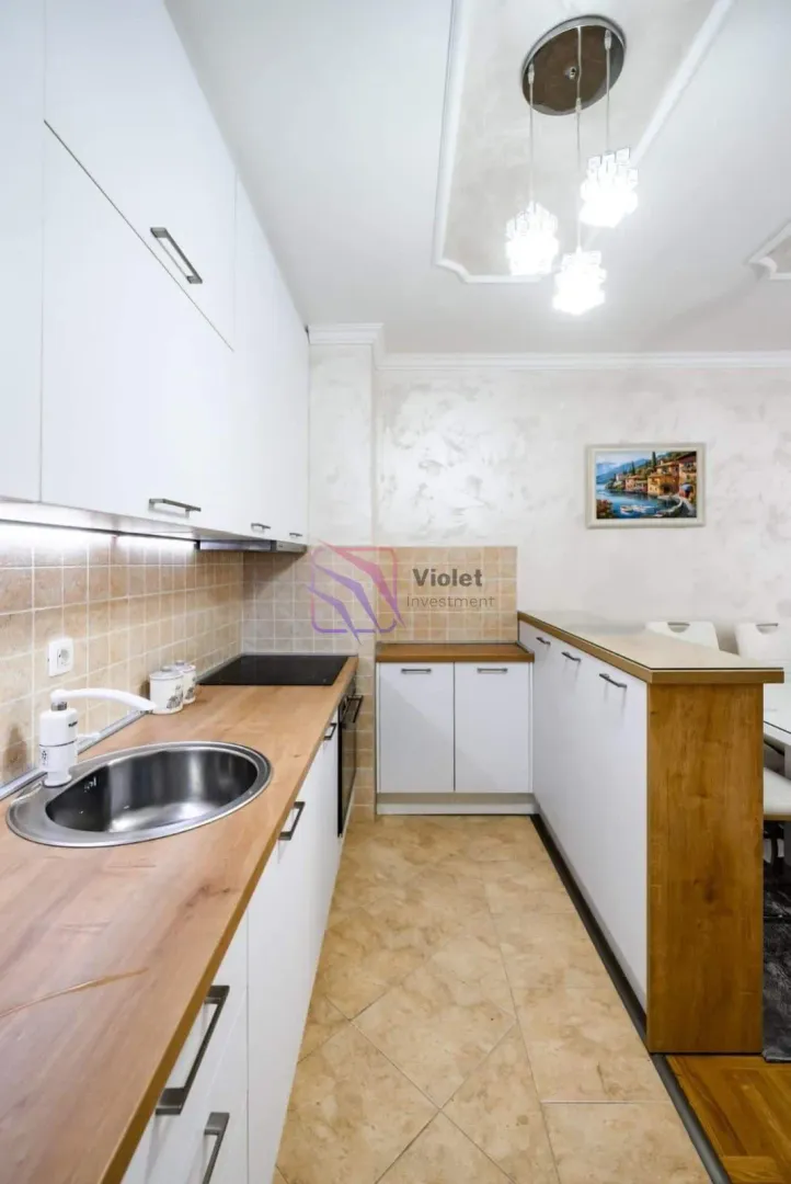 Kitchen with white cabinetry, wooden countertops, and a breakfast bar.