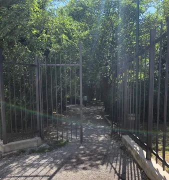 Dvorište sa metalnom kapijom i stazom okruženom zelenilom. - image 11