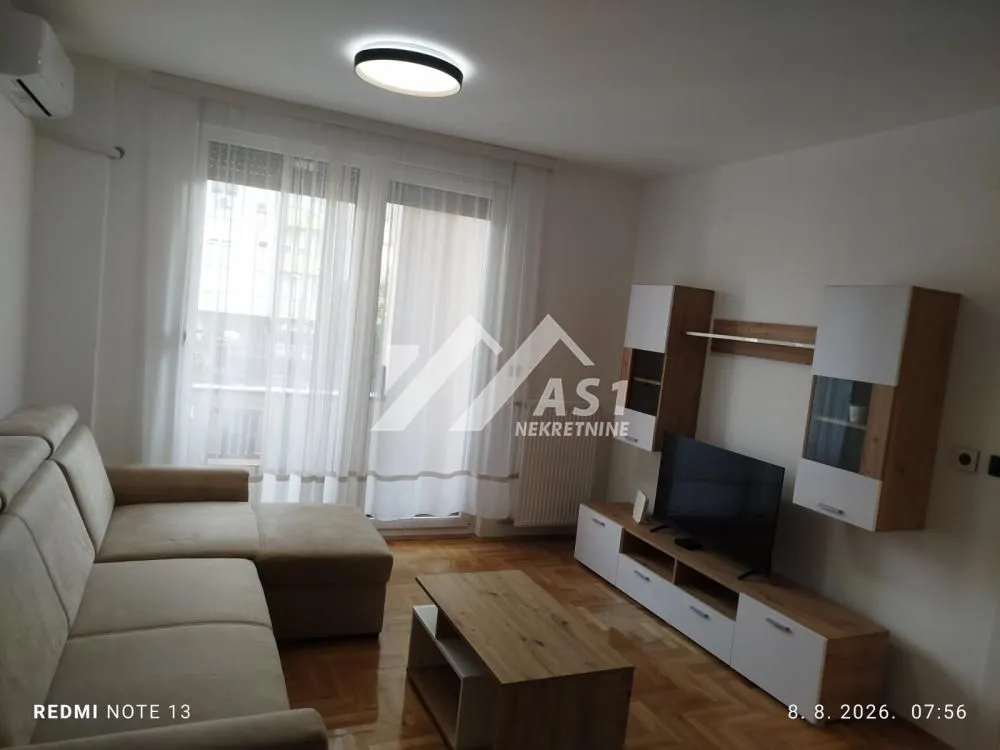 Dnevna soba sa garniturom, televizorom i izlazom na terasu.