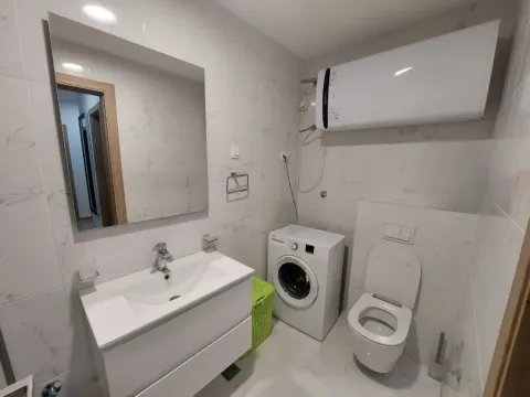 Modernly equipped bathroom with a washbasin, toilet, washing machine, and water heater. - image 9