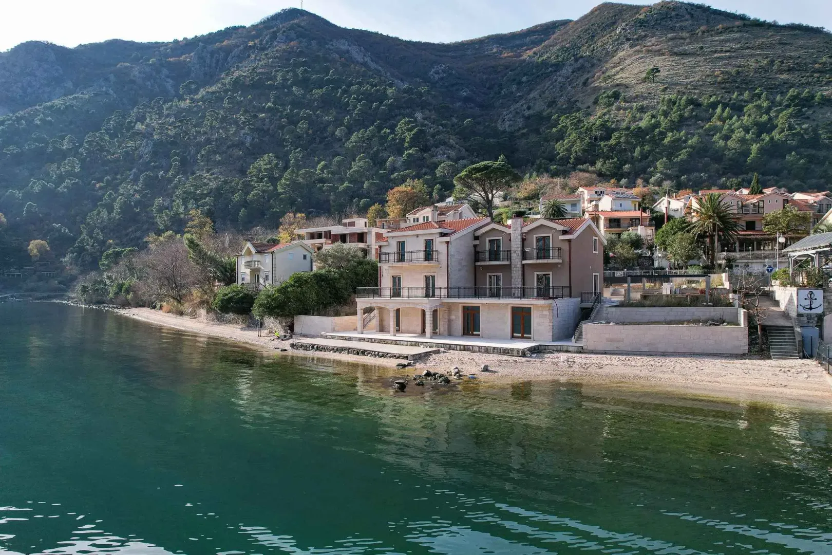 Pogled na višespratnu kuću na obali mora sa okolinom.