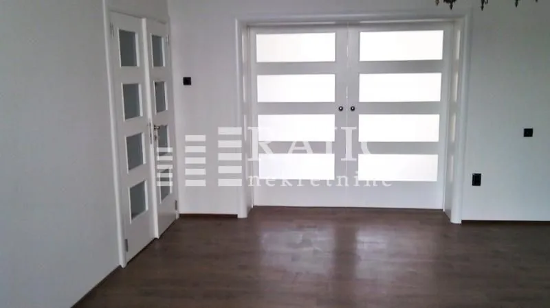 Interior of a room with white doors and dark wooden flooring.