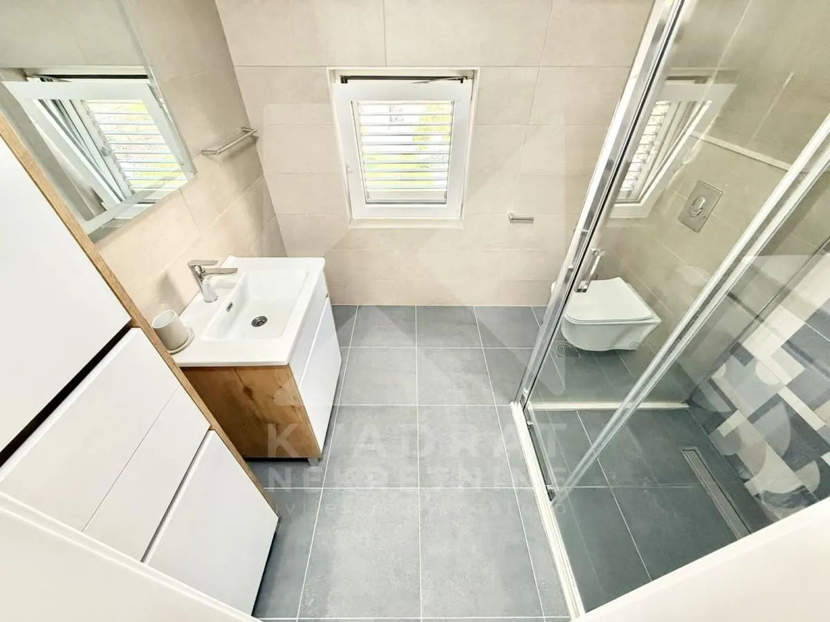 Modern bathroom with a shower cabin, washbasin, and toilet.