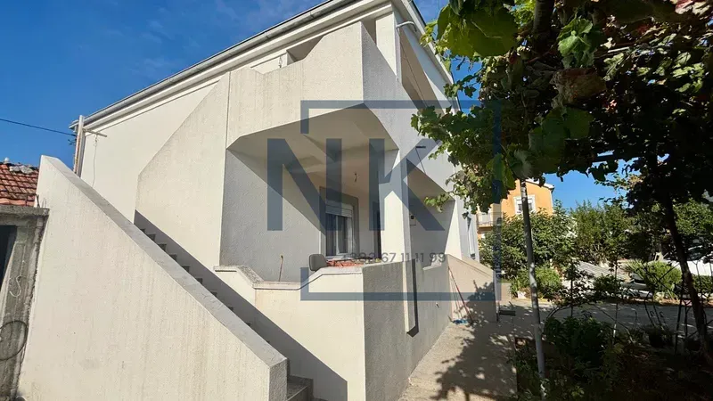 Exterior view of the house with a balcony and outdoor stairs.