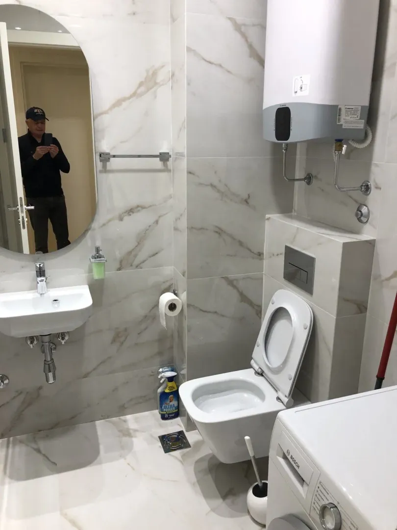 Svijetlo kupatilo sa modernim sanitarijama i veš mašinom.