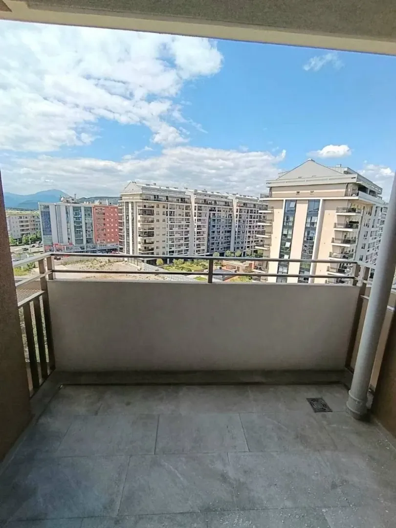 Manji popločani balkon sa pogledom na grad i okolne zgrade.