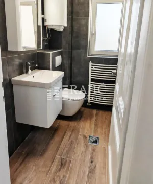 Moderno opremljeno kupatilo sa tamnim pločicama i drvenim podom. - image 8