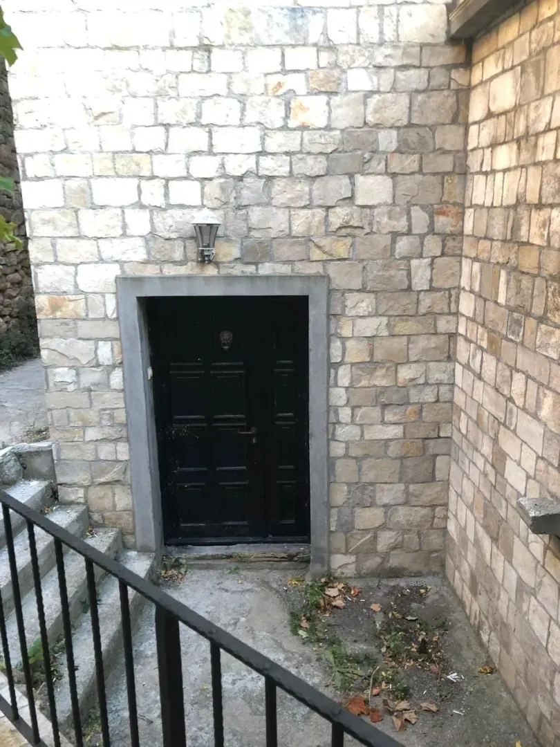 Ulazna vrata kuće sa kamenom fasadom i spoljnim stepeništem.
