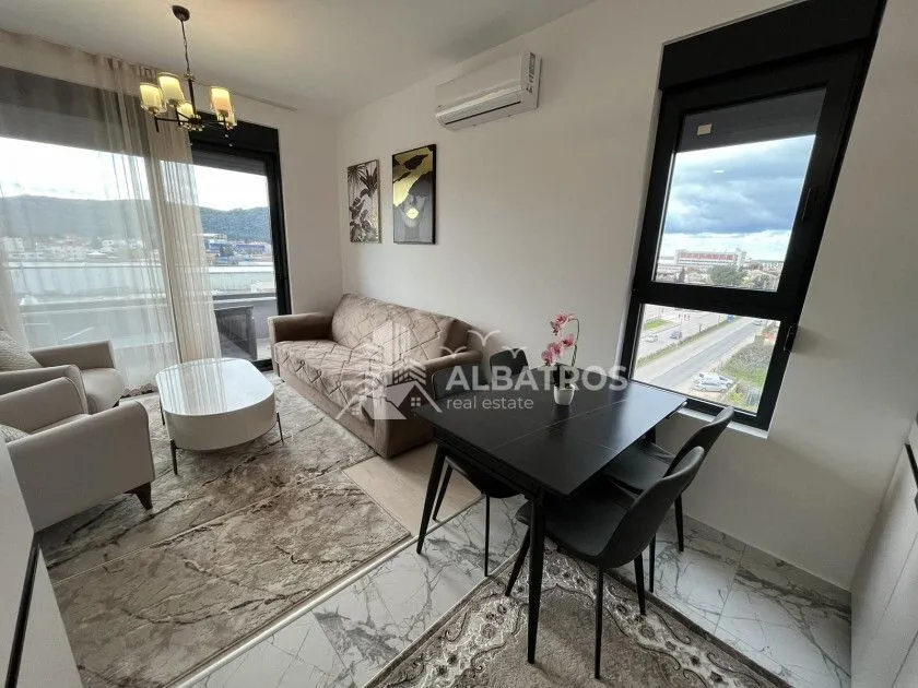 Living room with a sofa, dining table, and access to the terrace.