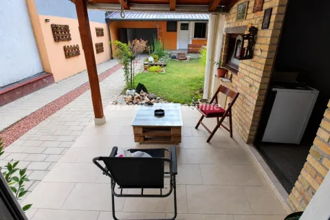 Natkrivena terasa sa stolom i stolicama i pogledom na uređeno dvorište. - image 14