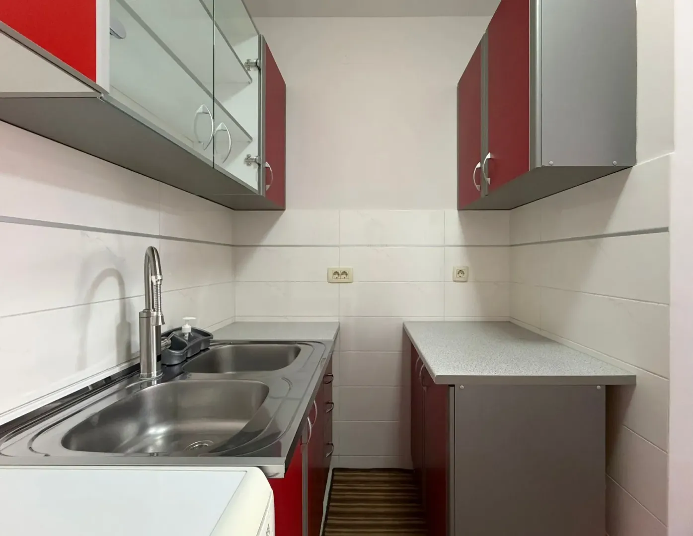 Small kitchen with a sink and red cabinetry.