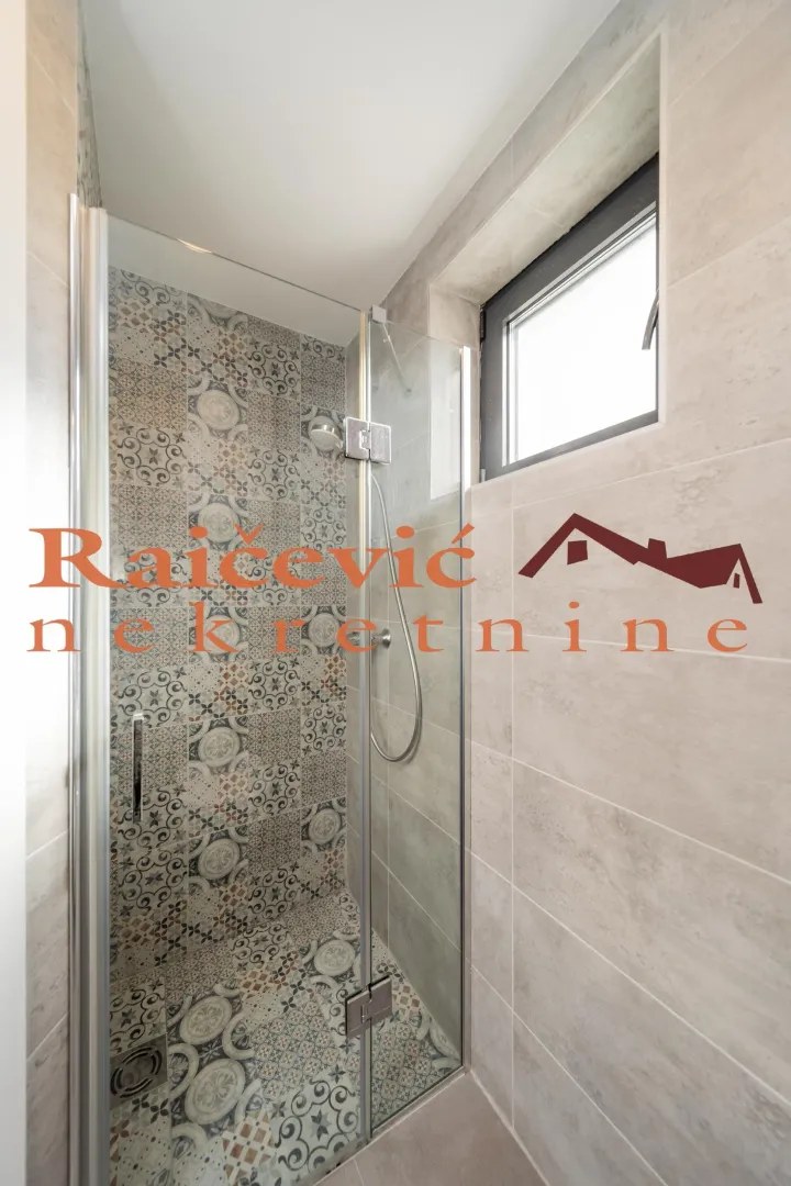 Walk-in shower with a glass partition and decorative tiles in the bathroom.