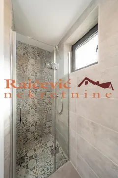 Walk-in shower with a glass partition and decorative tiles in the bathroom. - image 10