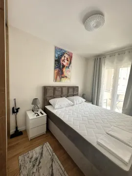Svijetla spavaća soba sa francuskim ležajem, noćnim ormarićem i izlazom na balkon. - image 6