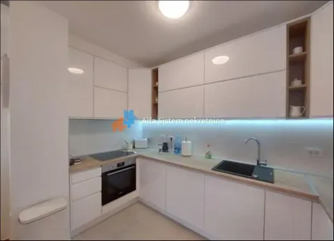 Modern L-shaped kitchen with white cabinets and a wooden countertop. - image 9