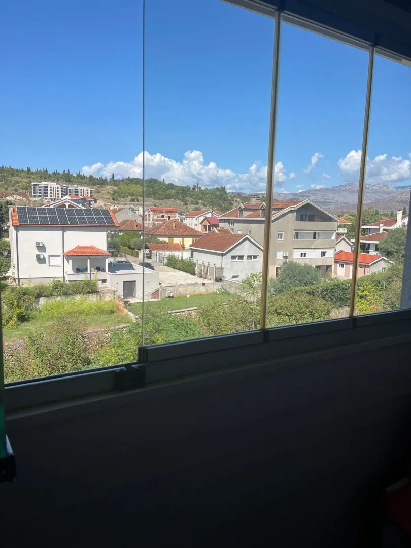 View of the neighborhood and surrounding mountains through a glazed terrace.