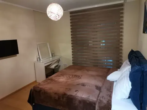 Furnished bedroom with a double bed, a desk, and a wall-mounted TV. - image 5