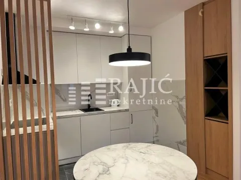 Modern kitchen with white cabinetry, dining table and a wooden partition panel. - image 3