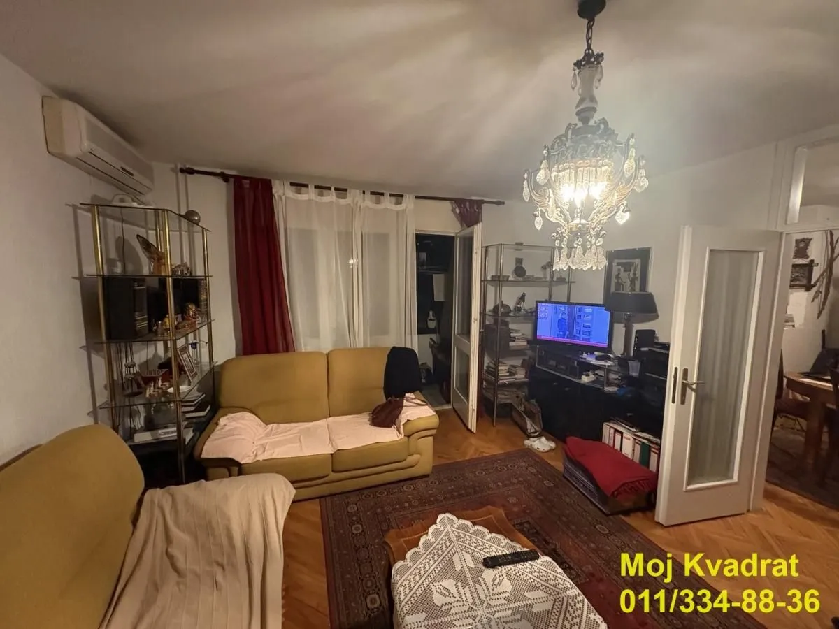 Dnevna soba sa garniturom, televizorom i lusterom.