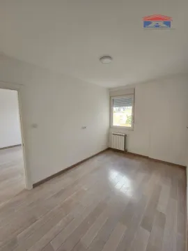 Prazna soba sa drvenim podom, belim zidovima i prozorom. - image 7