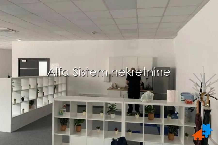 Office kitchen area with shelving units and a refrigerator.