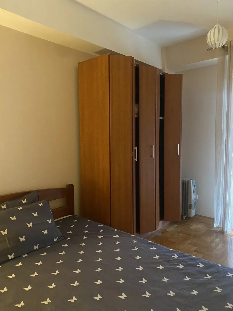 A bedroom with a large wooden wardrobe and a bed.