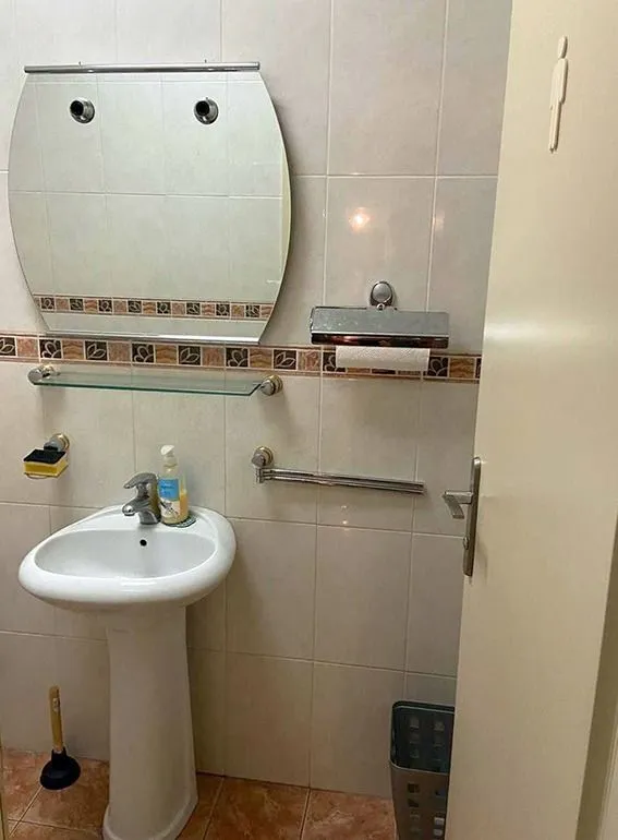 Small bathroom with a sink, mirror, and ceramic wall tiles.