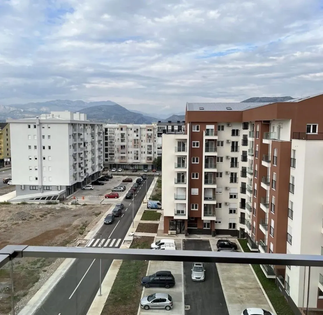 Pogled sa terase na okolne zgrade i planine u daljini.