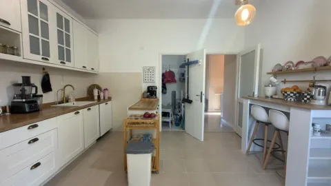 Moderna bijela kuhinja sa drvenim elementima i trpezarijskim šankom. - image 6