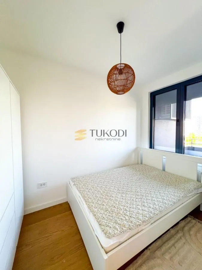 Bright bedroom with a white bed, wardrobe, and pendant light.