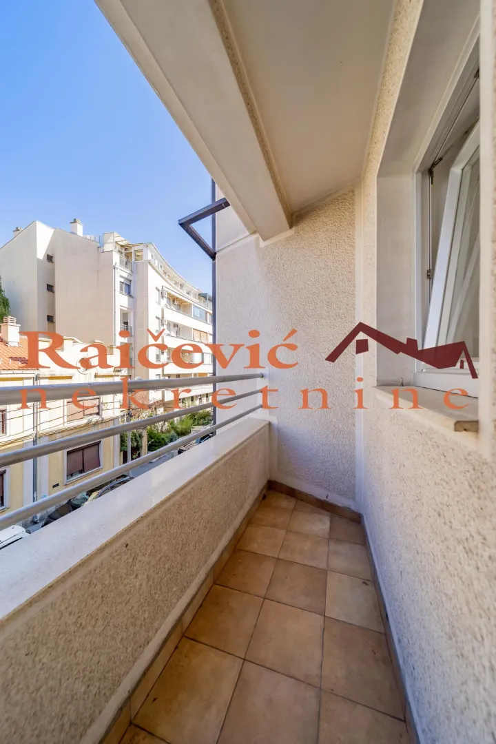 Natkriveni balkon sa pogledom na ulicu i okolne zgrade.