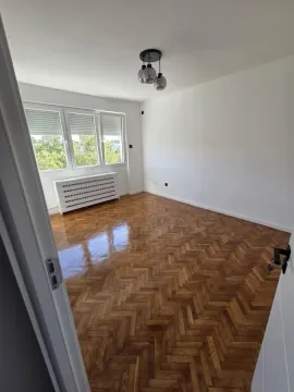 Prazna soba sa parketom i belim zidovima. - image 2