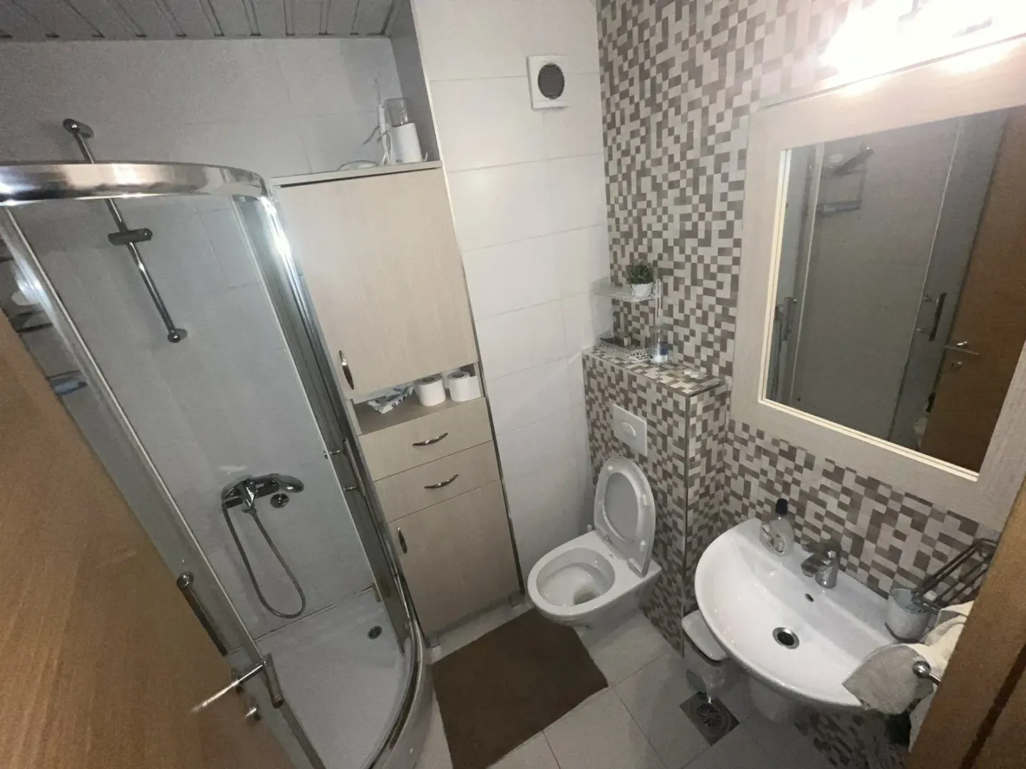 A functional bathroom with a shower cabin, toilet, and sink.