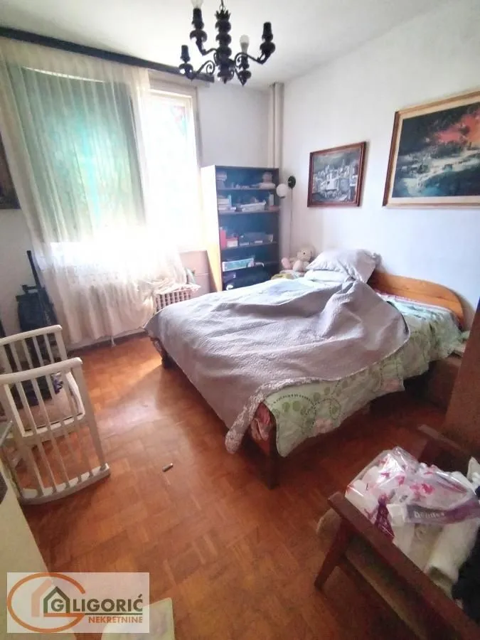 Spavaća soba sa krevetom, dečjim krevecom i prozorom sa zavesama.