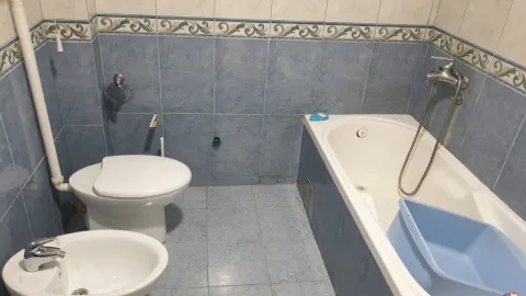 A bathroom featuring blue ceramic tiles, a bathtub, a bidet, and a toilet. - image 15
