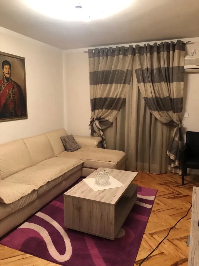 Dnevna soba sa ugaonom garniturom, stočićem i parketom.