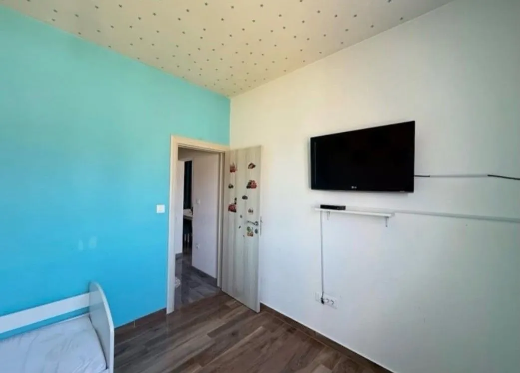 Children's bedroom with a bed, a blue accent wall, and a wall-mounted TV.