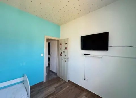 Children's bedroom with a bed, a blue accent wall, and a wall-mounted TV. - image 6