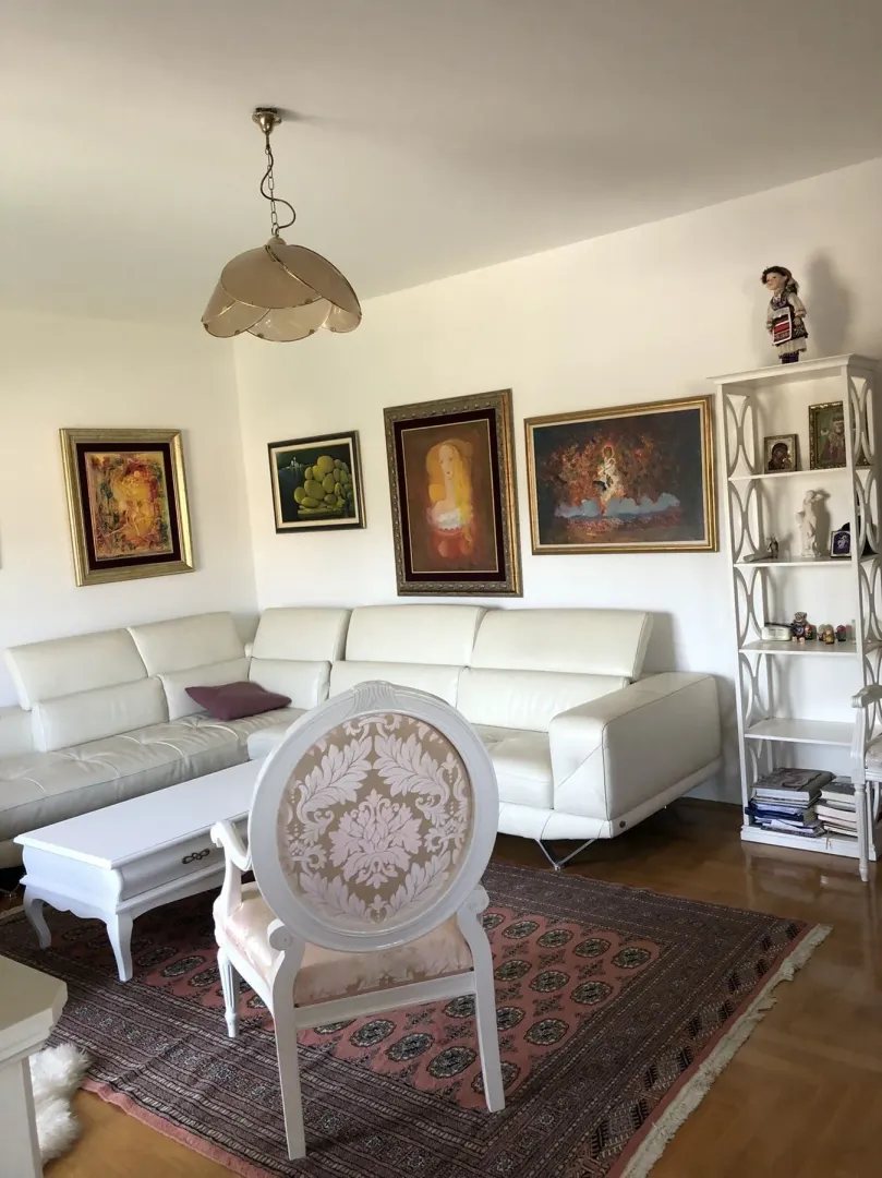 Bright living room with a white corner sofa and decorative armchair.
