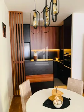 Modern kitchen with dark cabinetry and a dining table in the foreground. - image 2