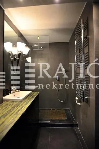 Modern bathroom with a washbasin and a walk-in shower in dark tones.